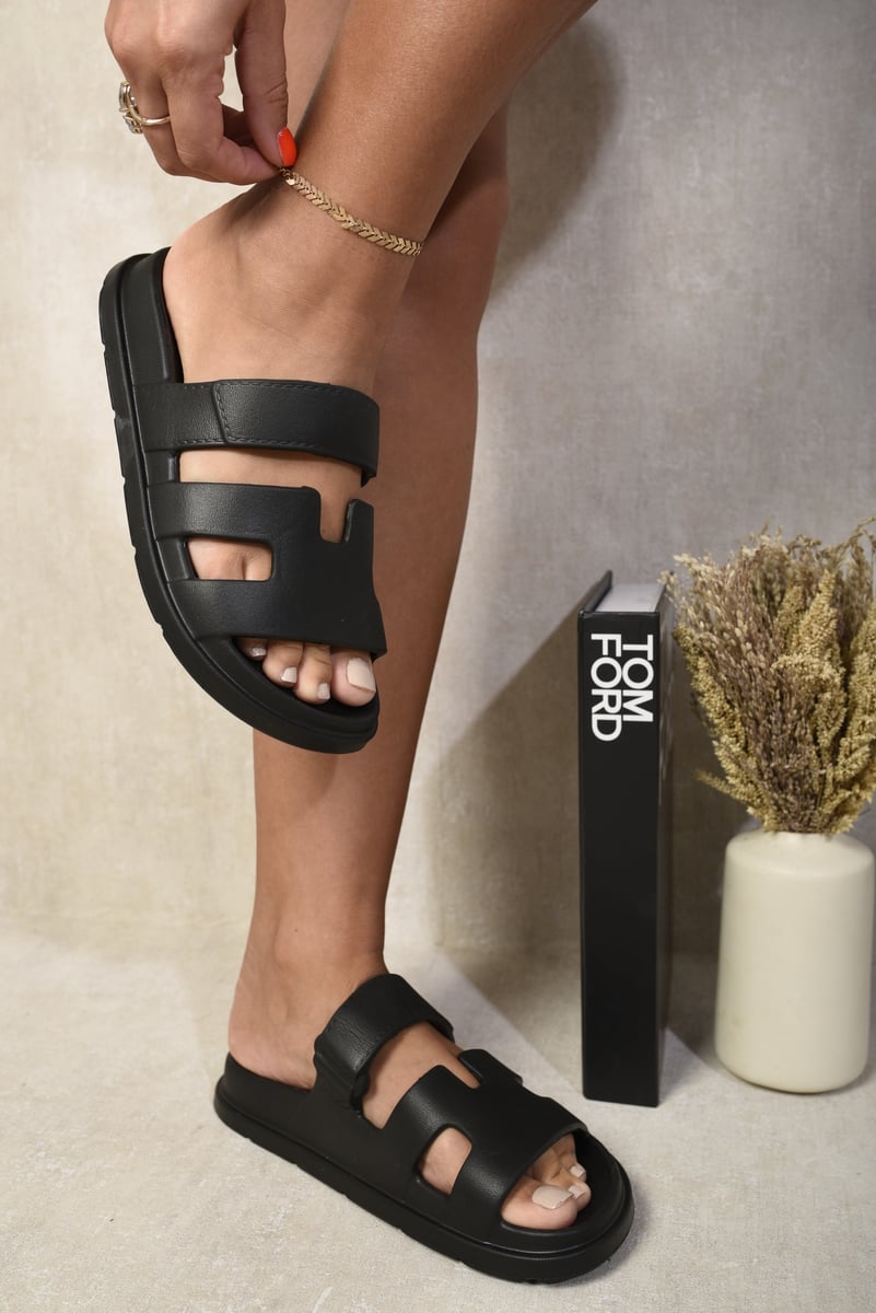 Black slide sandals with wide straps and geometric cutout panels