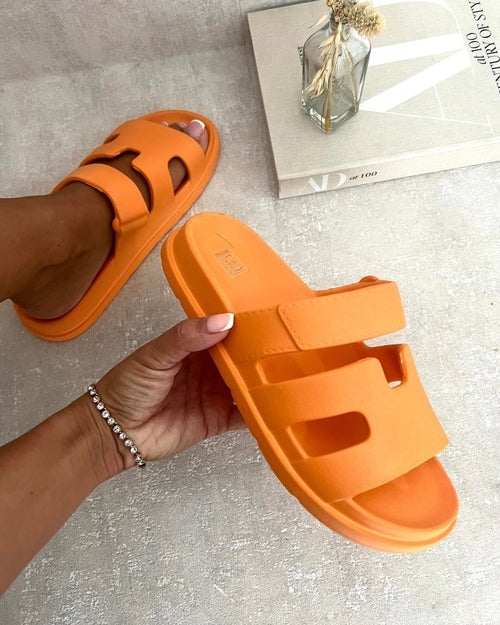 Orange slide sandals with geometric cutout straps, slip-on style