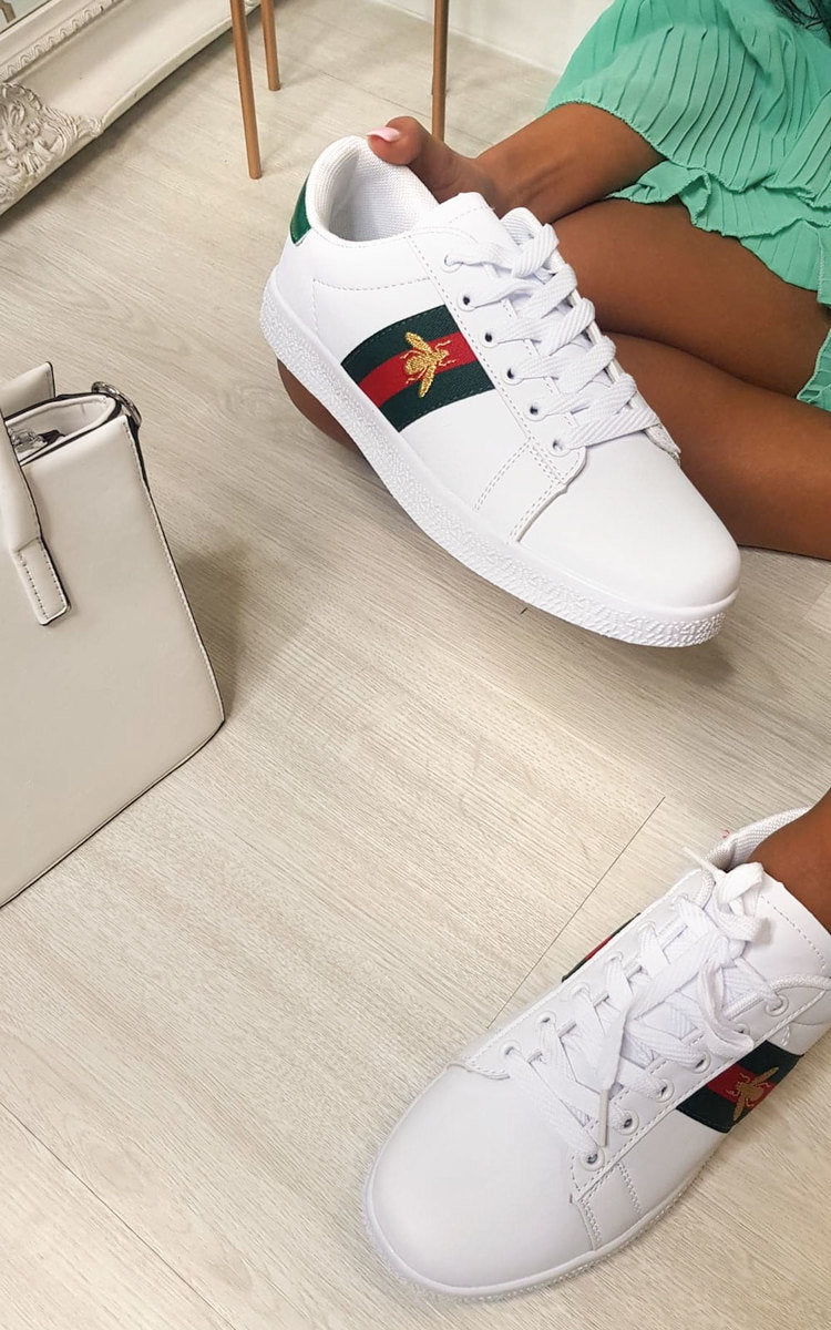 White lace-up trainers with colorful side panel, worn with light green pants