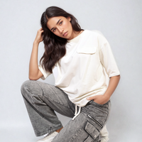 Grey cargo jeans with drawstring waist, multiple pocket panels, relaxed kneeling pose