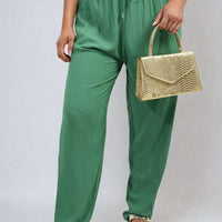 Green high-waist drawstring trousers with side pockets and flowing straight-leg fit