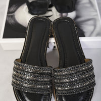 Black flat slide sandals with wide rhinestone straps and glossy black footbed