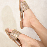 Gold flat slide sandals with wide embellished straps and flat tan outsole