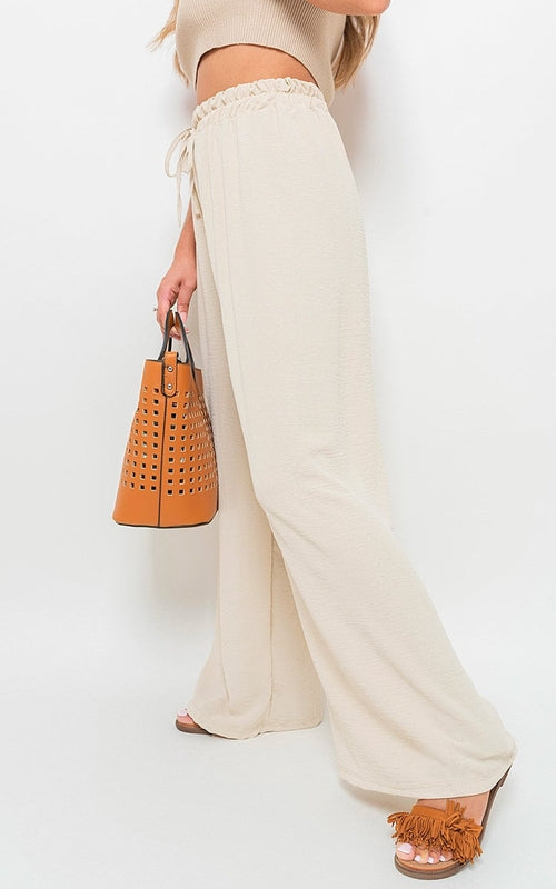 Beige wide-leg trousers with drawstring gathered waist and soft, billowy fabric