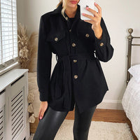 Black belted jacket with button front, flap pockets, and long sleeves in a fitted waist.