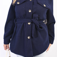 Navy belted jacket with button front, flap pockets, and roll-tab collar.