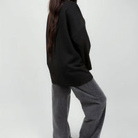 Oversized black sweatshirt with round neck and long sleeves, side profile.