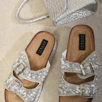 Sparkly silver double-buckle platform sandals with tan footbeds, pair view