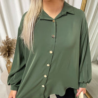 Oversized collared button-down top in dark green, close-up of collar and gold button placket.