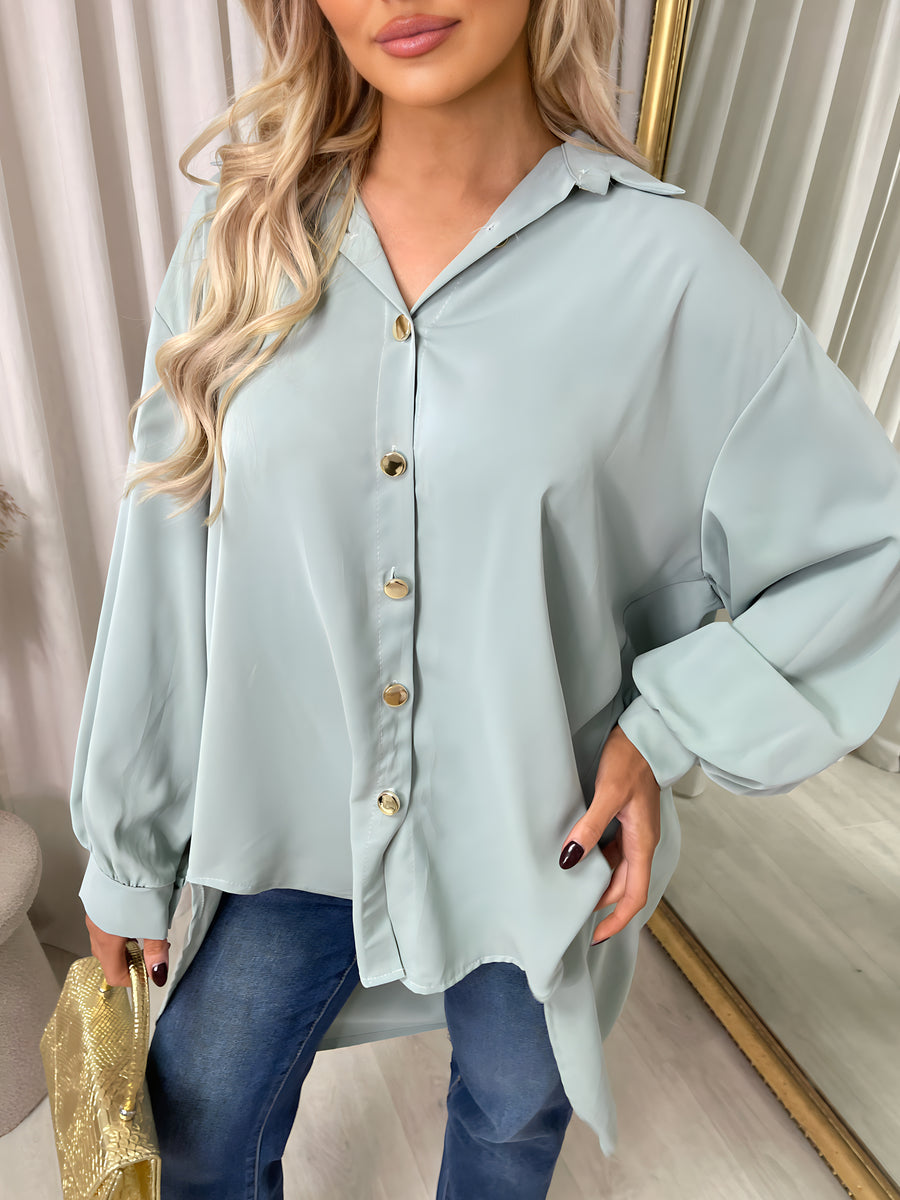 Light blue collared button-down top close-up with front buttons and gathered cuffs