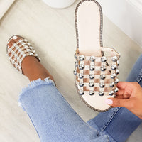 Nude flat slide sandals with studded lattice straps and rhinestone studs, angled view