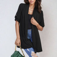 Black open-front cardigan with short sleeves, draped front, and side pockets