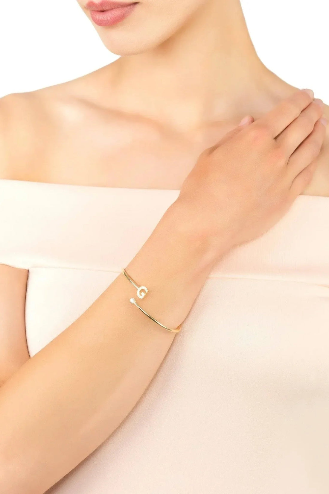Gold G bangle bracelet with small sparkle stones on wrist