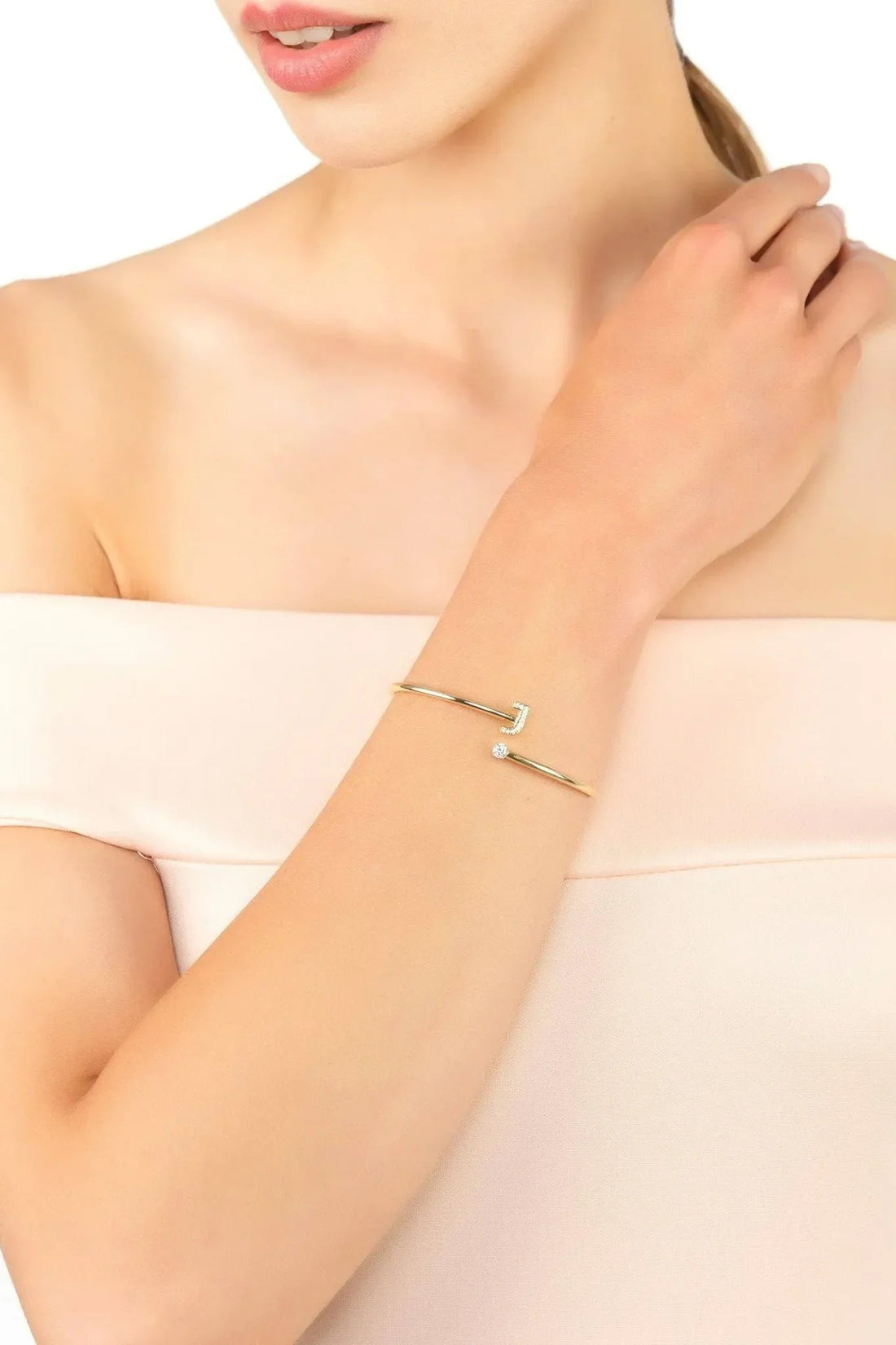 Gold-tone J initial bangle bracelet worn on wrist