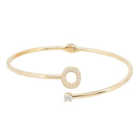 Gold-tone bangle featuring O initial ring charm and small central stone