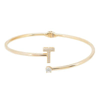 Gold-tone bangle bracelet featuring a vertical T with small crystal accents