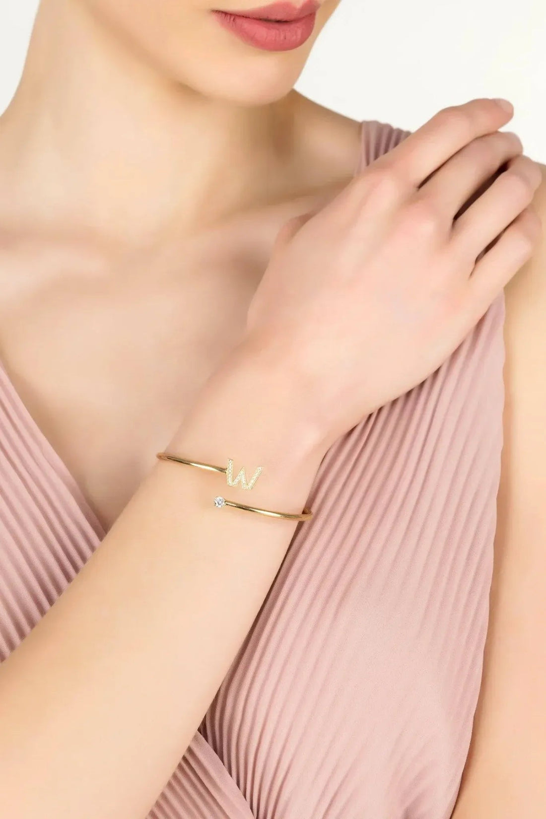 Gold W initial bangle worn on wrist, with small crystal W and stones