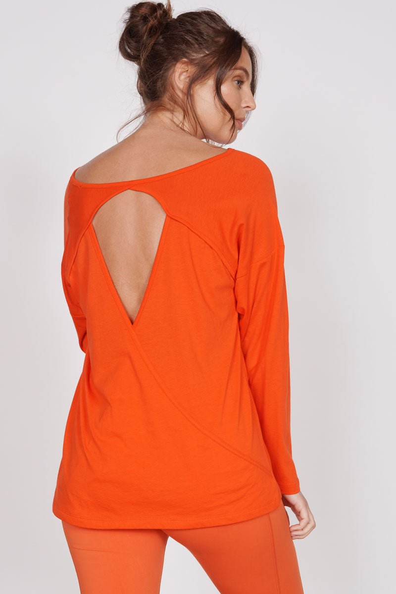 Back view: orange training top with keyhole cutout and open back panel
