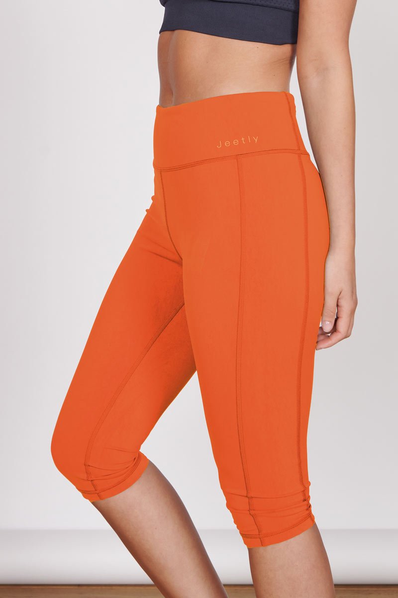Orange 3/4 sports leggings, hidden zip pocket detail and knee-length hem