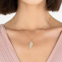 Gold angel wing pendant necklace on neckline with thin chain and wing charm