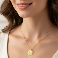 Gold zodiac talisman necklace with round Libra pendant and blue crystal, worn close-up