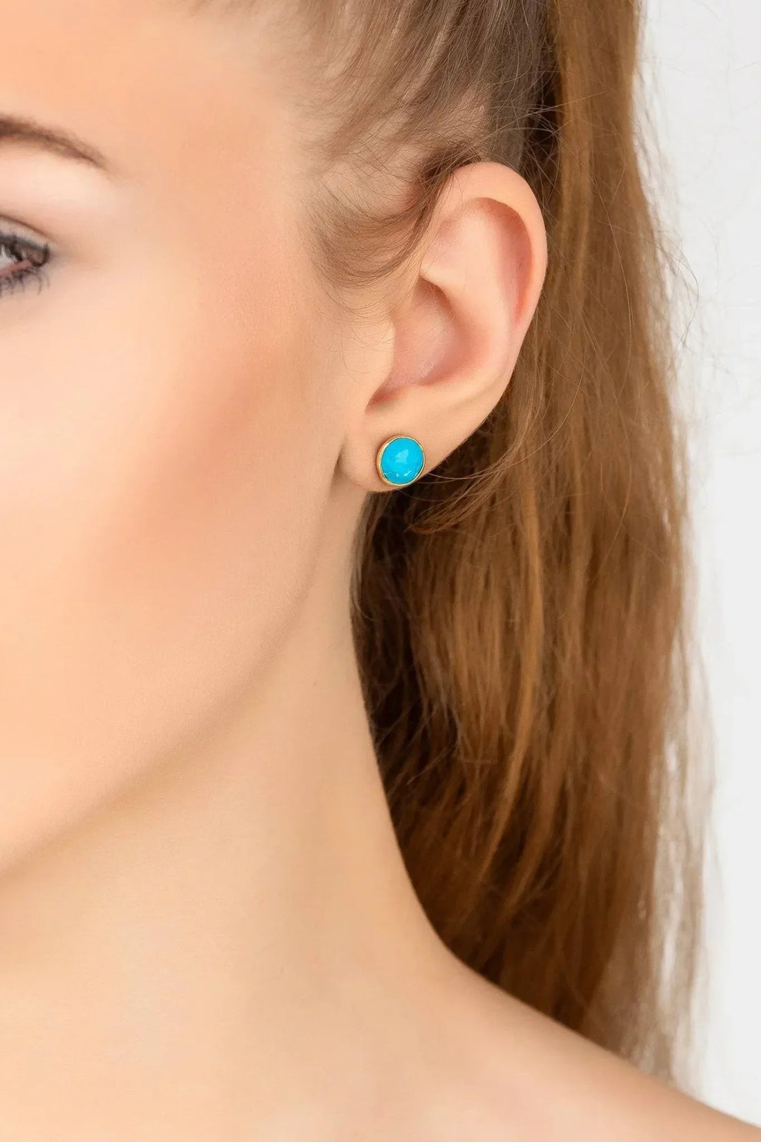 Gold hoop earrings with round turquoise gemstone, shown on ear