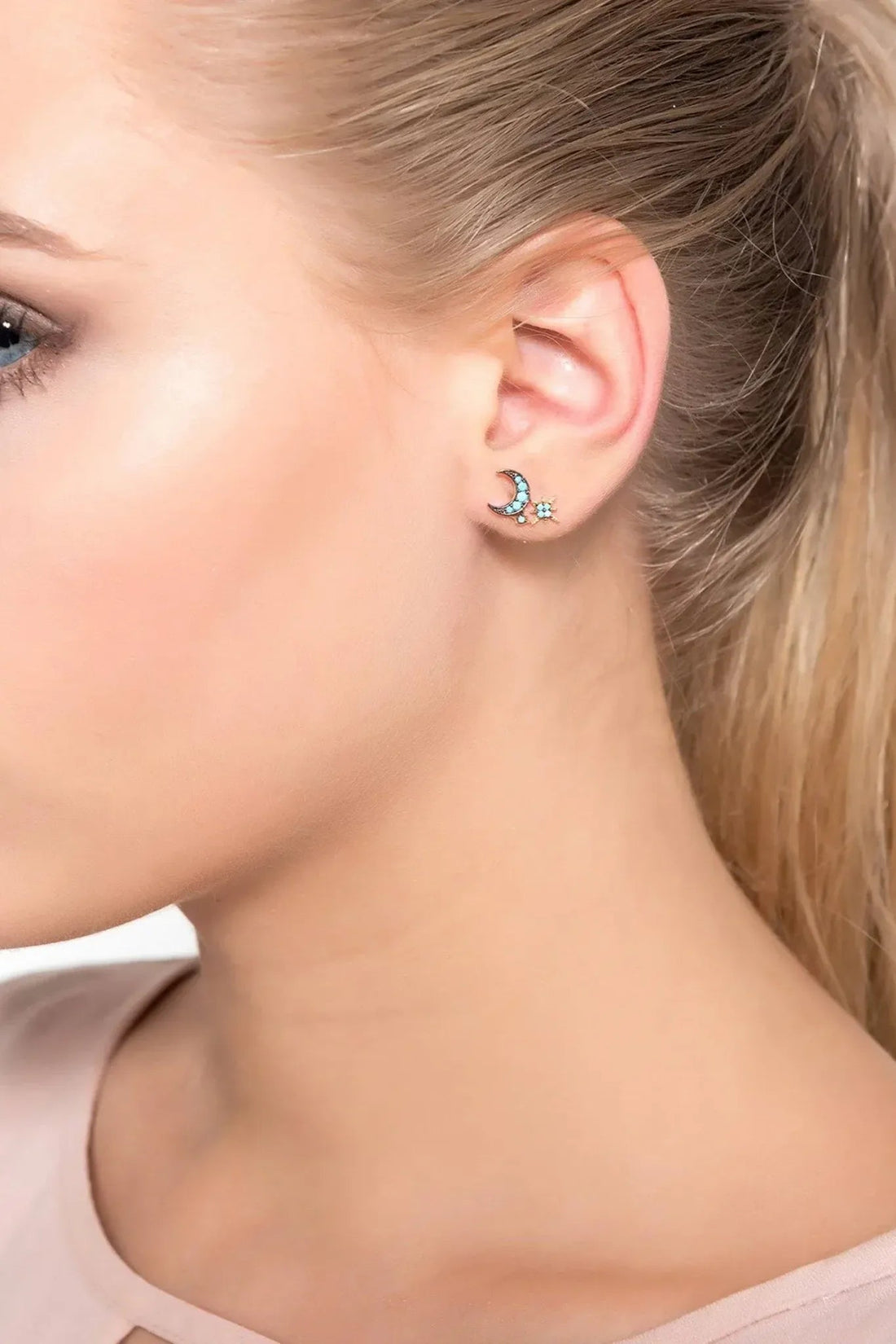 Turquoise moon and starburst stud earrings worn on ear