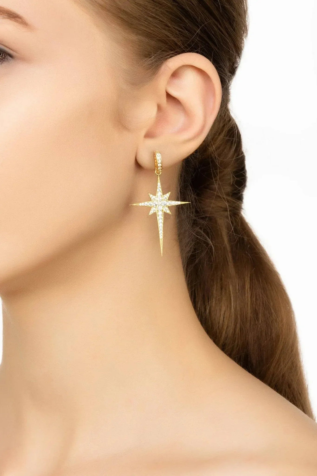 Gold star drop earrings with sparkling starburst and long pointed drop on ear