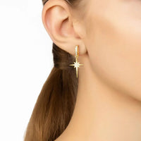 Gold star drop earrings with crystal sparkle worn on the ear