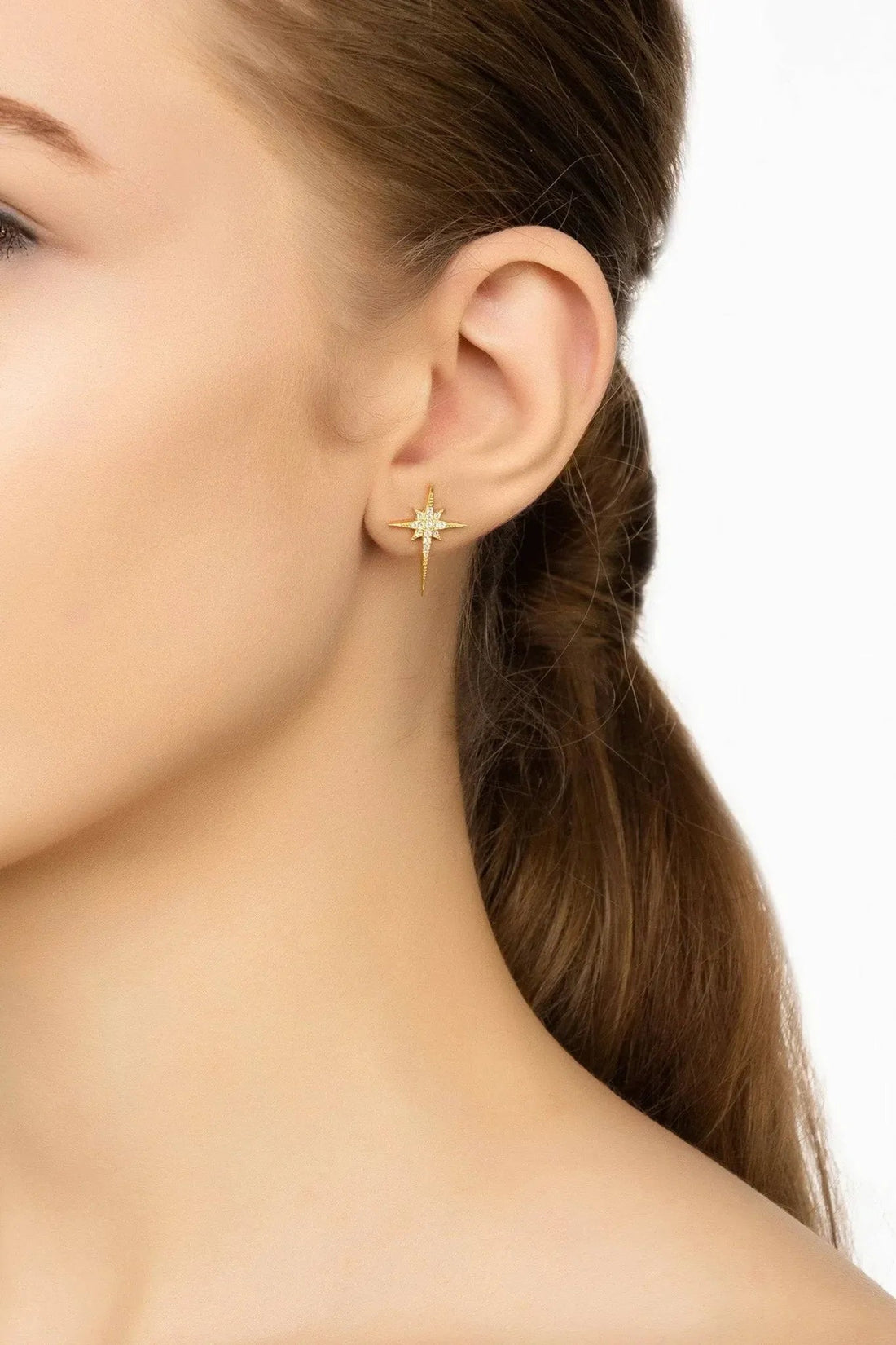 Gold star stud earrings with crystal stones and small dangling drop on ear