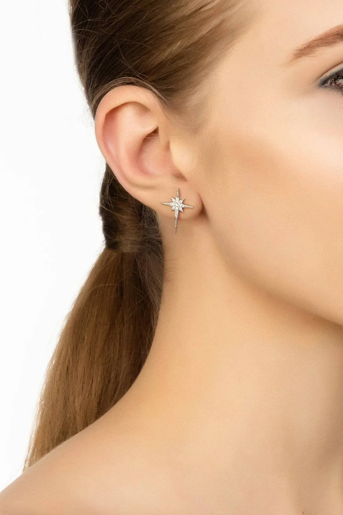 Silver star stud earrings on ear, small sparkling star with drop detail
