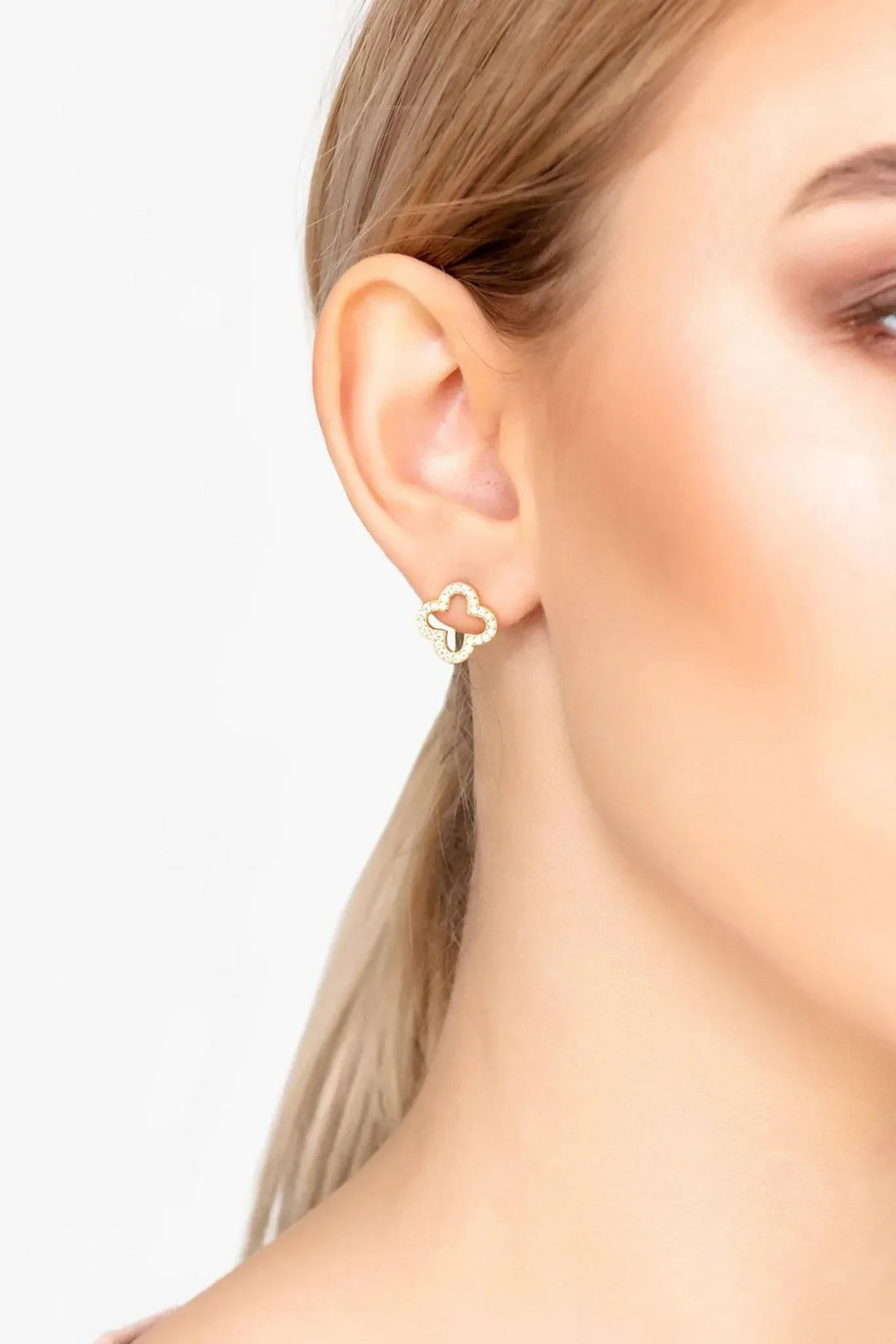 Gold clover stud earrings on a woman&