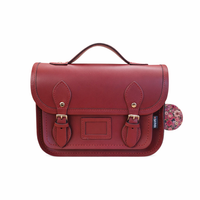Oxblood leather midi satchel with top handle, flap front, and floral-lined side pouch