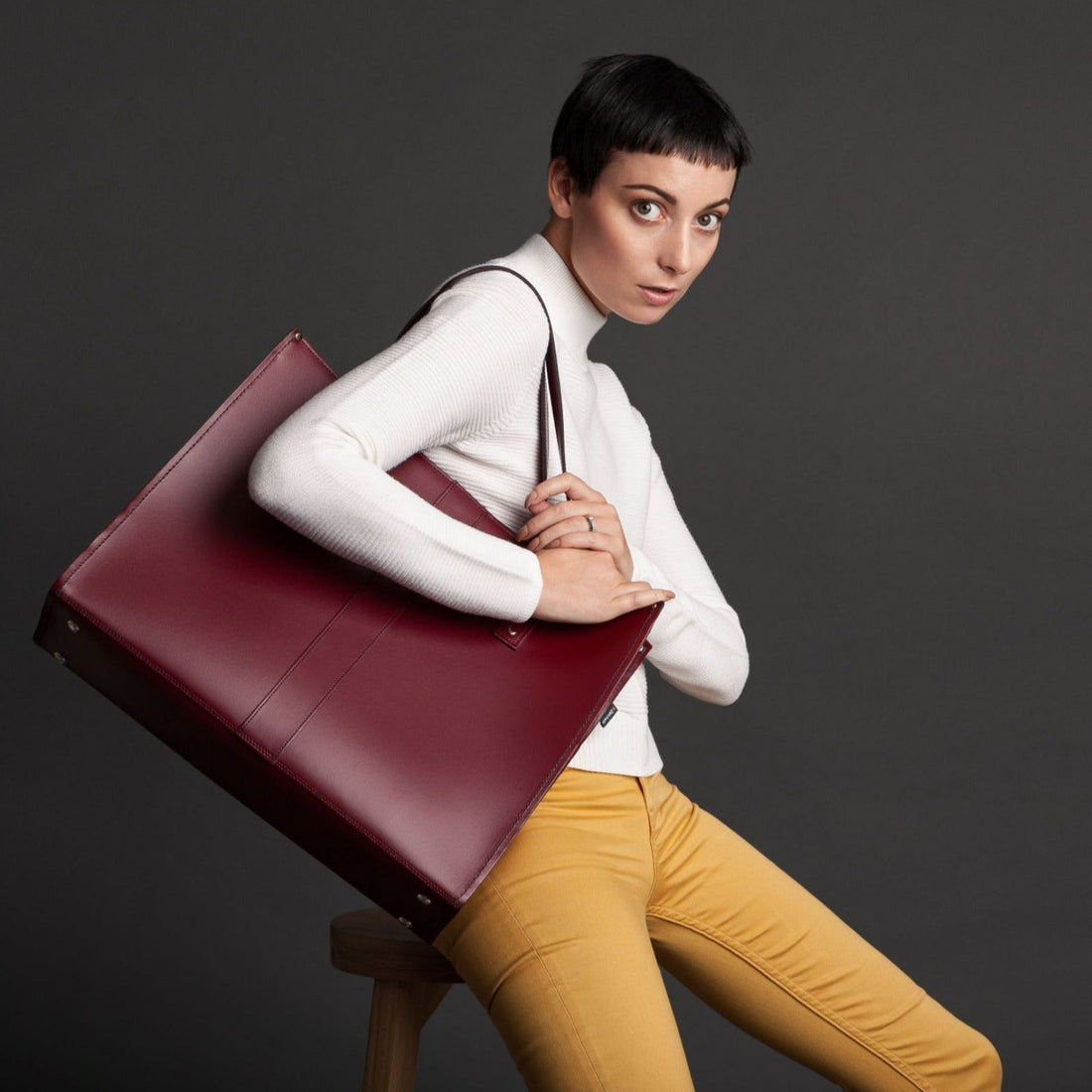 Maroon leather tote bag with wide shoulder strap and top handle