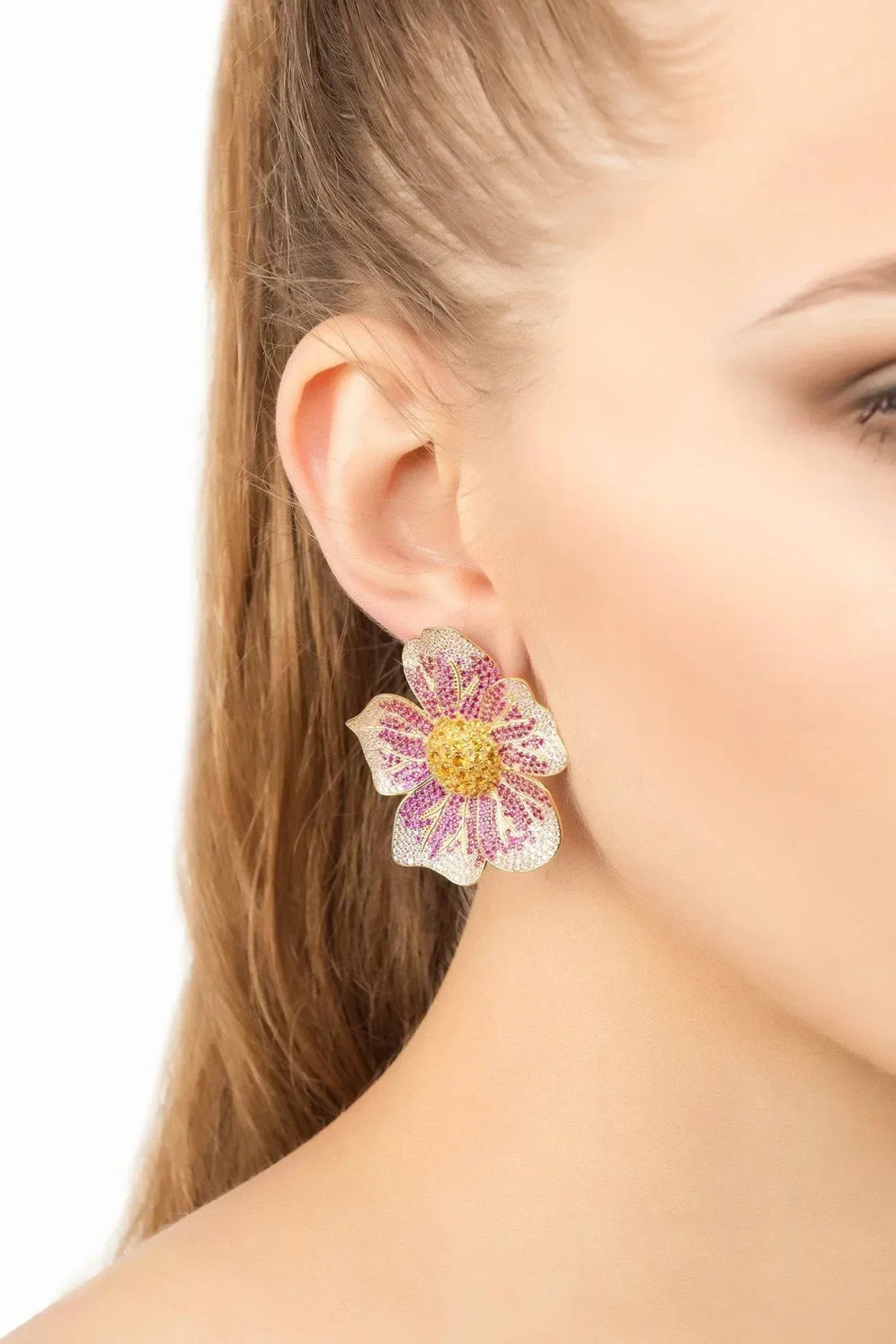 Beaded flower earrings on ear with pink and purple petals and gold-tone posts.