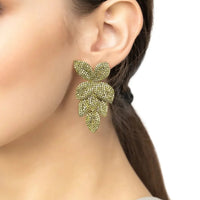 Green peridot CZ flower drop earrings on a model’s ear, gold-tone posts