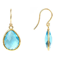Gold-tone drop earrings with blue topaz teardrop stones, side view