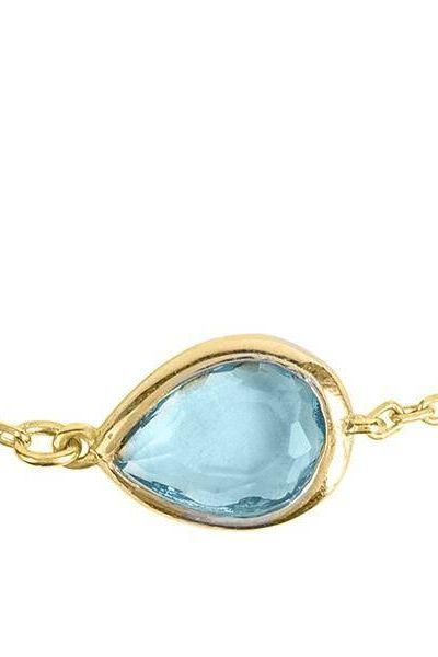 Gold bezel teardrop bracelet centerpiece with blue topaz stone