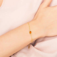 Gold mini teardrop bracelet on wrist with orange teardrop stone