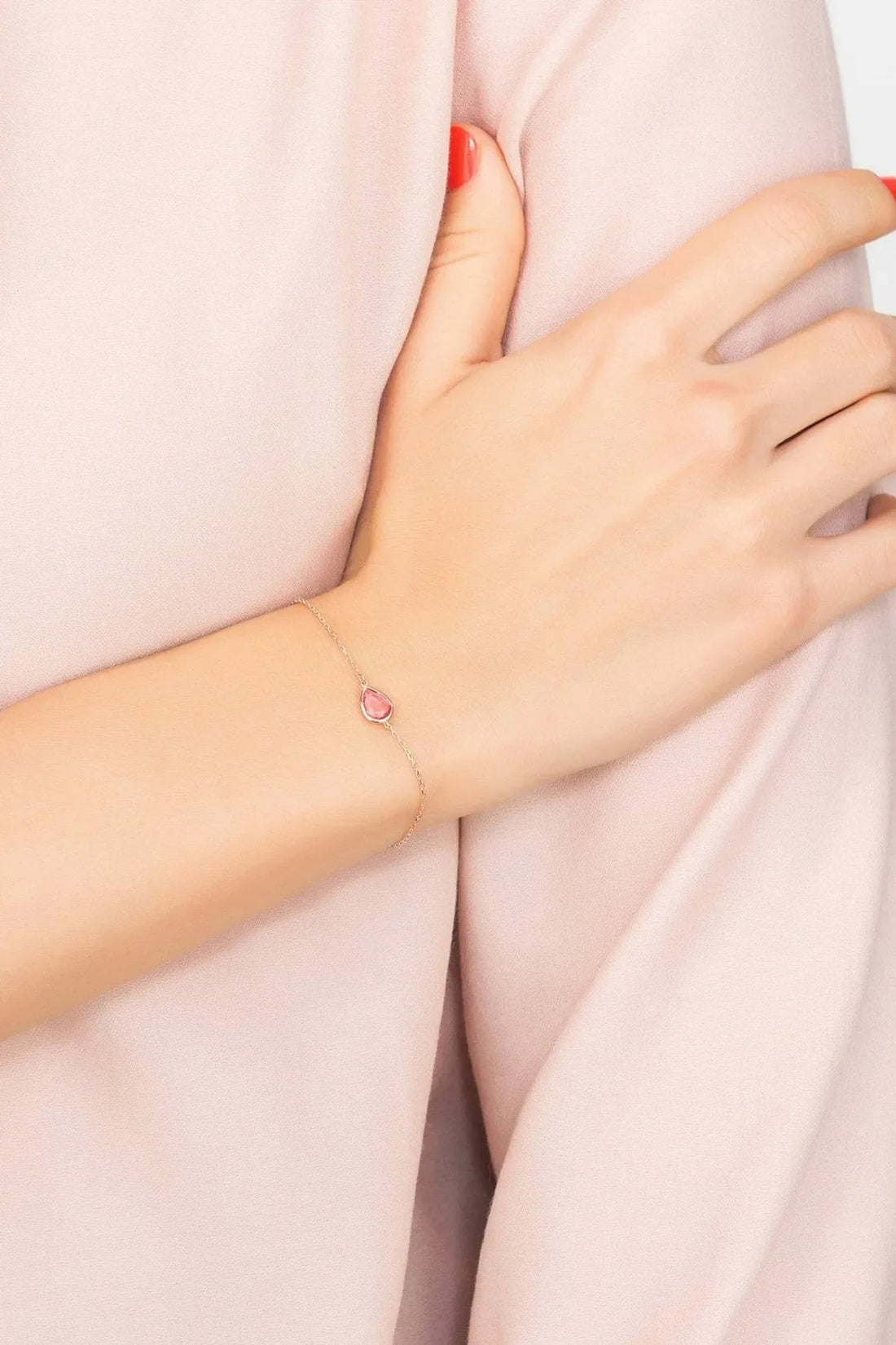 Rose-gold teardrop bracelet with pink gemstone on wrist