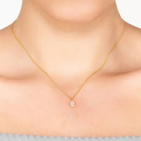 Gold mini teardrop pendant necklace worn at the collarbone