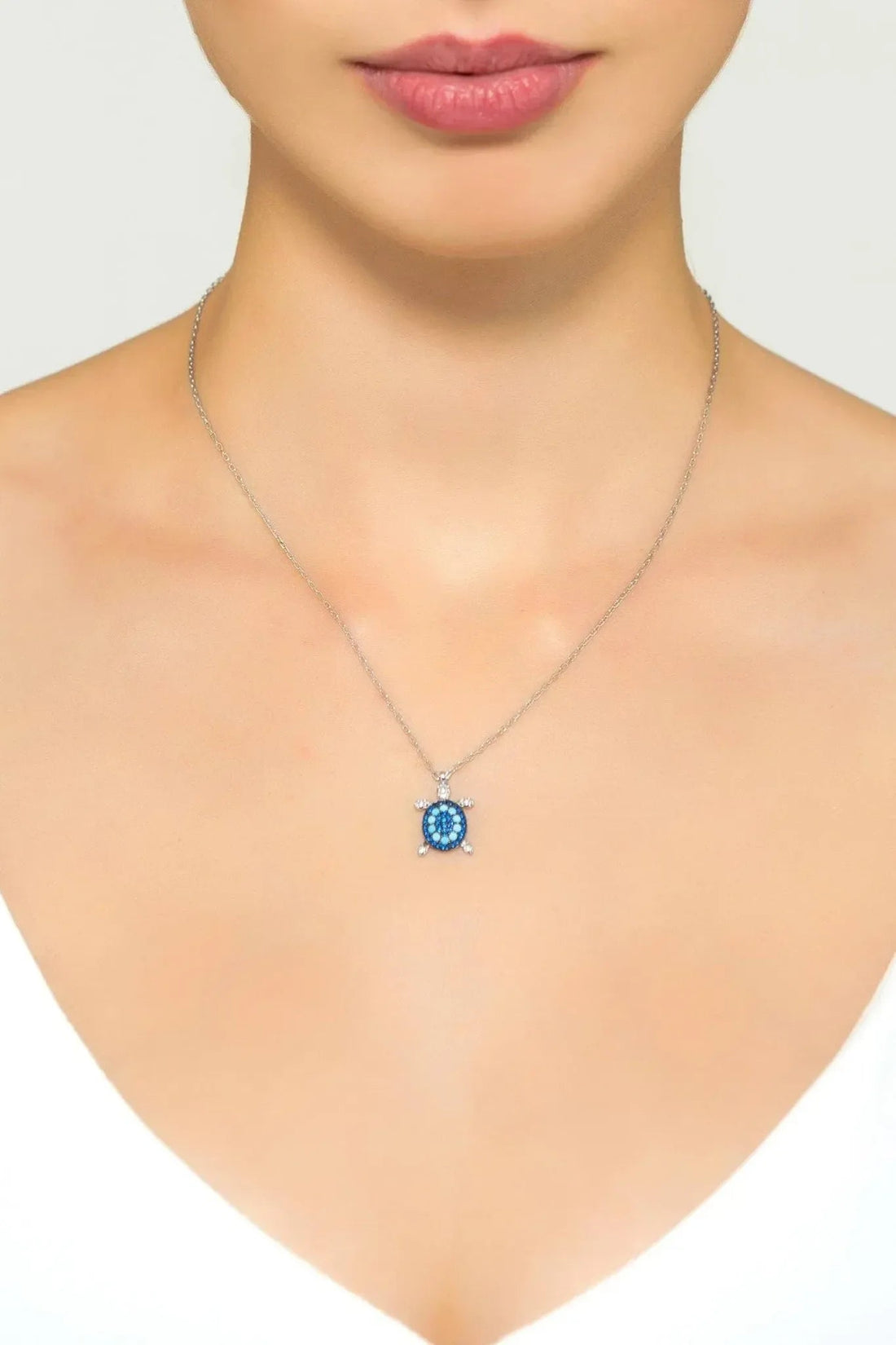 Silver pendant necklace with small round blue turtle charm on chain