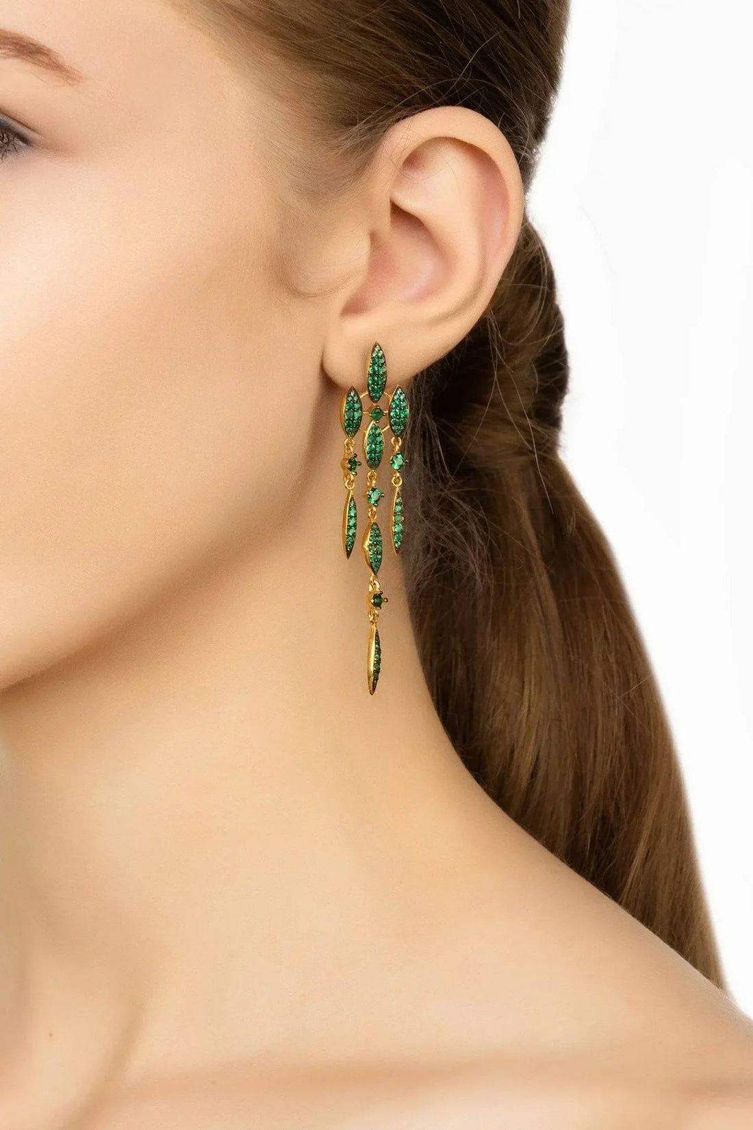 Emerald green CZ drop earrings on ear with gold-tone hooks