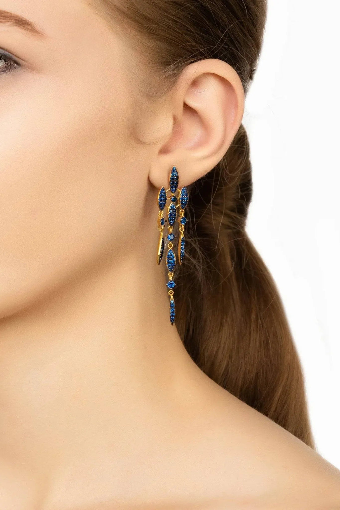Sapphire-blue CZ drop earrings hanging from gold hoops