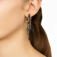 Sapphire-blue CZ drop earrings hanging from gold hoops