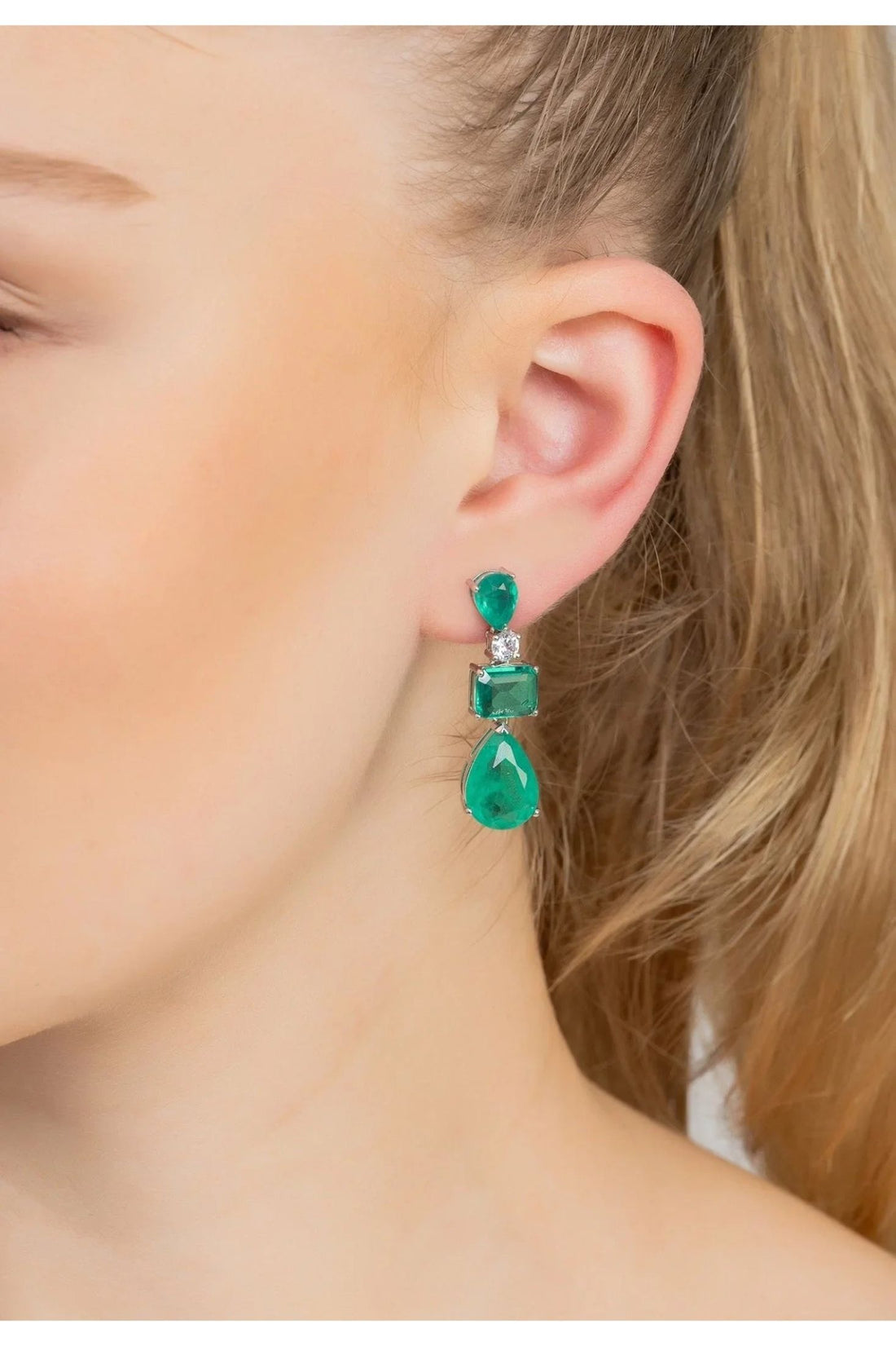 Silver drop earrings with green teardrop and square stones, seen on a hook ear back