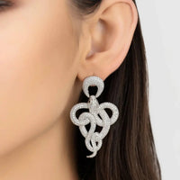 Silver rhinestone drop earrings with braided knot design on model's ear