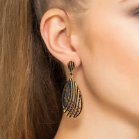 Black CZ teardrop earrings with gold-toned lattice detail, worn on the ear