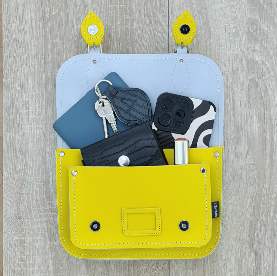 Open pastel yellow leather satchel with interior pocket holding small items