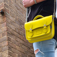 Pastel yellow leather satchel with shoulder strap, front flap, and buckled details